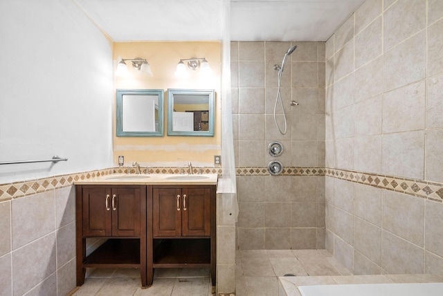 full bath with double vanity, tile patterned floors, tiled shower, and a sink