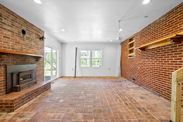 unfurnished living room featuring brick floor, recessed lighting, a wood stove, and brick wall