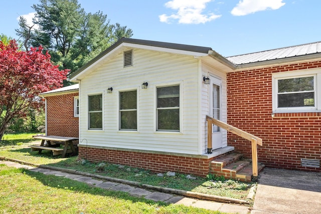 view of front facade featuring entry steps, crawl space, and metal roof