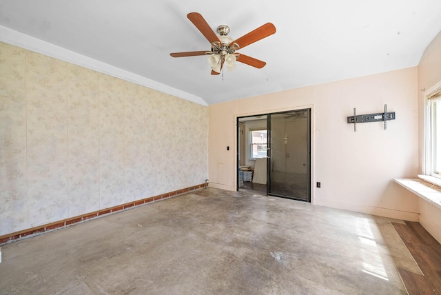 empty room with concrete floors, a ceiling fan, wallpapered walls, and baseboards