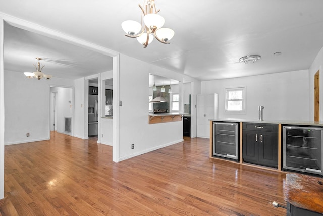 interior space with light wood-type flooring, visible vents, wine cooler, and an inviting chandelier