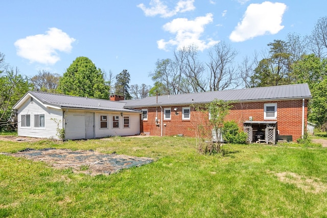 rear view of property with a lawn, a chimney, brick siding, and metal roof