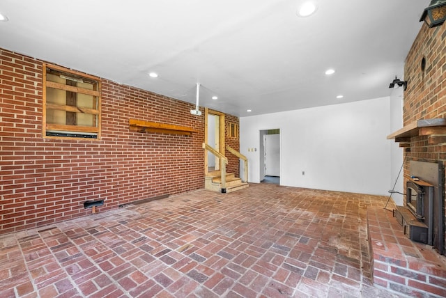 unfurnished living room with recessed lighting, brick floor, and stairway