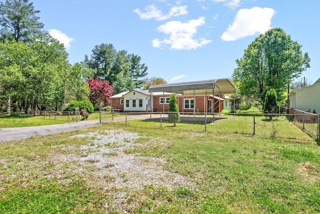 view of yard with a detached carport, a fenced backyard, and driveway