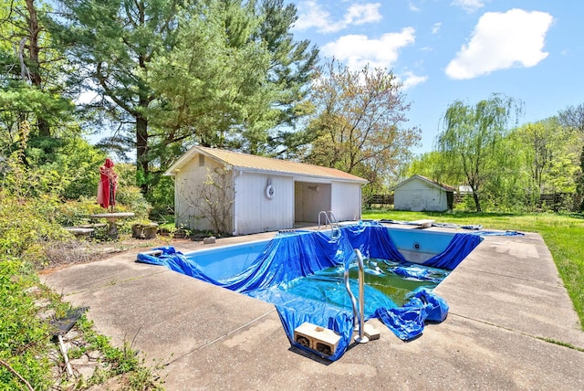 view of swimming pool with a covered pool, an outbuilding, a patio, and a storage shed