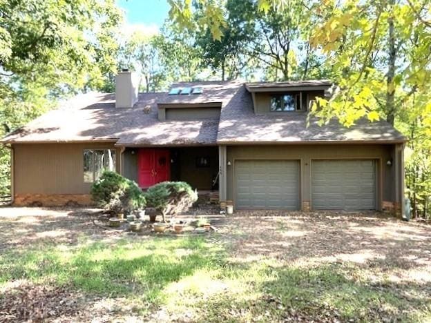 view of front facade with a chimney, a garage, and driveway