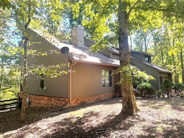 view of property exterior featuring a chimney and fence