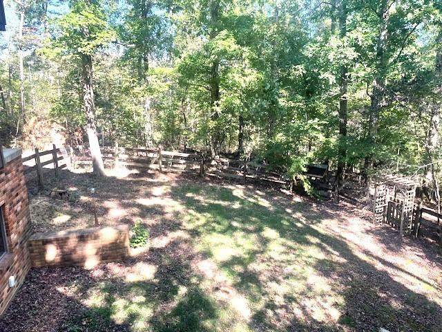 view of yard with a wooded view and fence