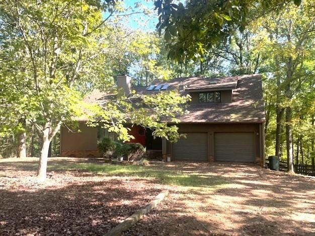 view of front of property featuring dirt driveway and a garage