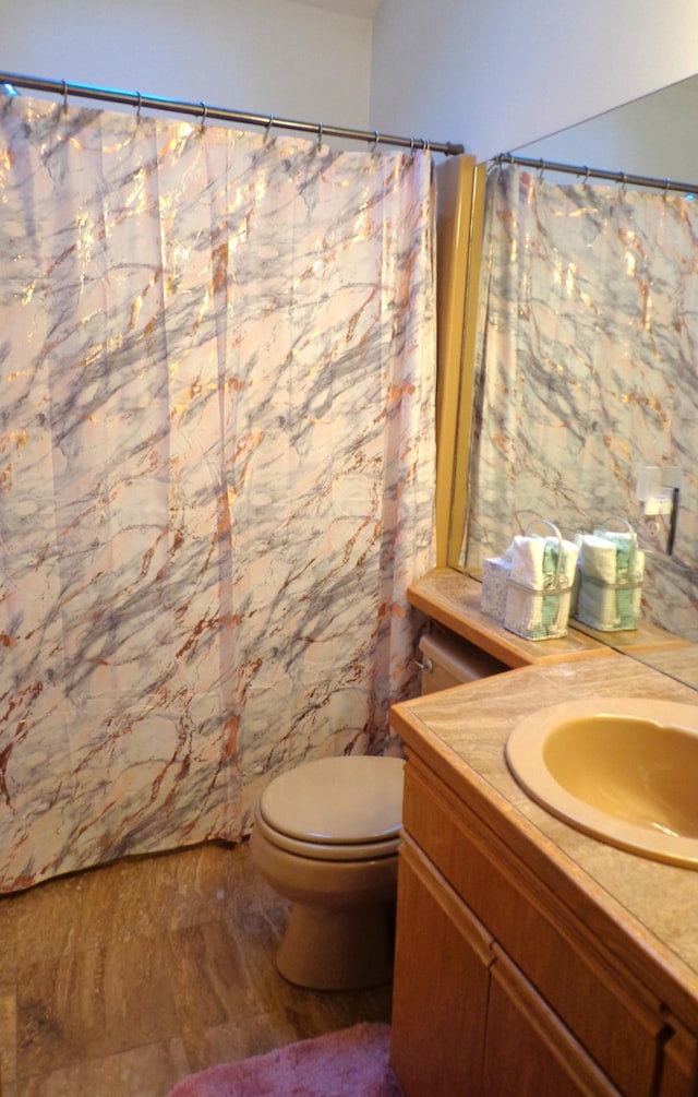 bathroom with toilet, vanity, and curtained shower