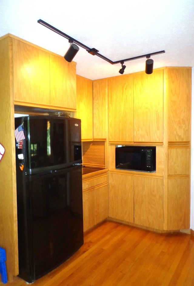 kitchen featuring black appliances, light wood-style floors, and track lighting