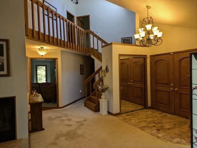 carpeted foyer featuring a towering ceiling, a chandelier, and stairway