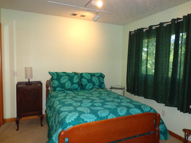 carpeted bedroom with rail lighting, baseboards, and visible vents