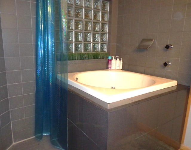 bathroom featuring a tile shower, tile walls, and a garden tub