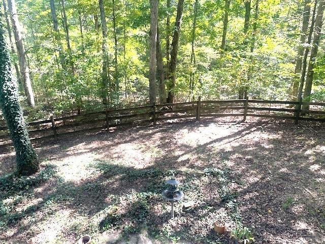 view of yard with a wooded view and fence