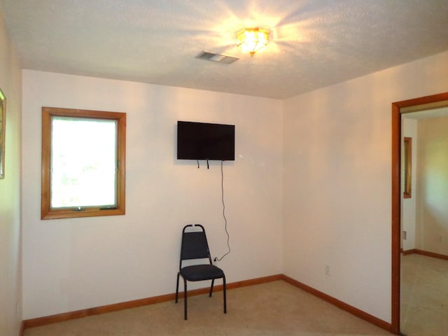 interior space with baseboards, visible vents, and light colored carpet