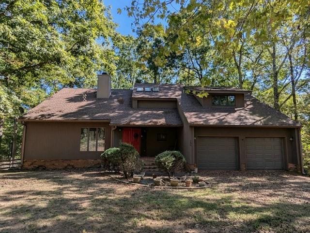 mid-century home featuring driveway, a chimney, an attached garage, and roof with shingles