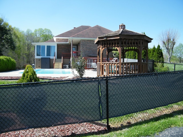 exterior space with a gazebo, a fenced in pool, fence, and brick siding