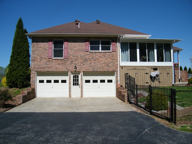 view of front of house with brick siding, an attached garage, fence, and aphalt driveway
