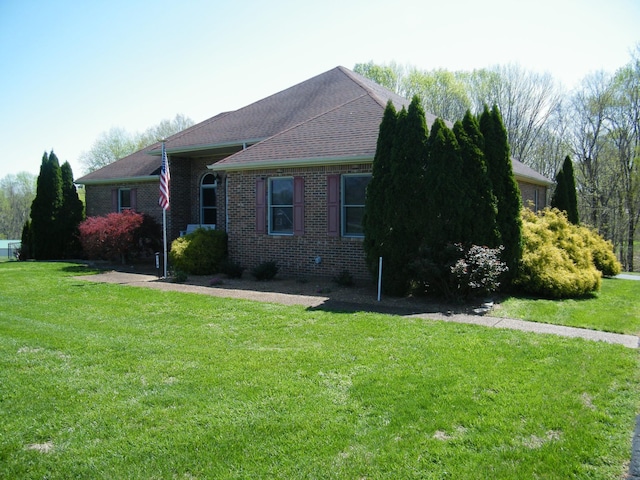 view of home's exterior featuring brick siding, a yard, and roof with shingles