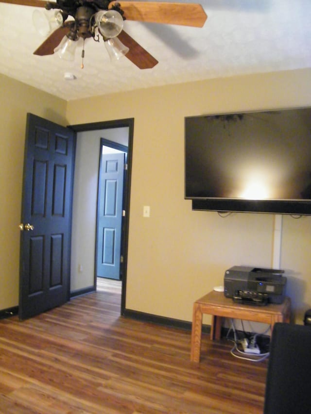 living area with ceiling fan, wood finished floors, and baseboards