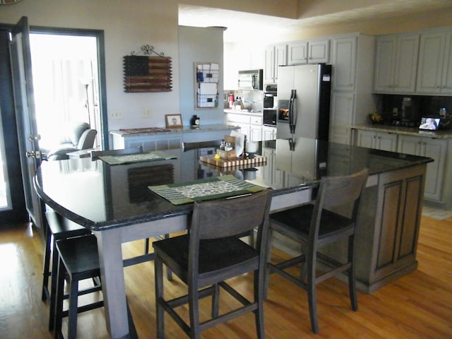 kitchen with a breakfast bar, a center island, wood finished floors, and appliances with stainless steel finishes