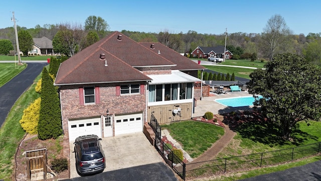 view of front facade featuring driveway, an attached garage, a front yard, brick siding, and fence