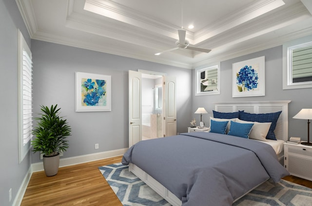 bedroom with baseboards, crown molding, wood finished floors, and a tray ceiling
