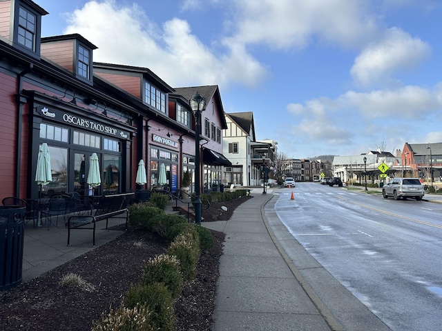 view of street featuring a residential view, sidewalks, curbs, and street lights