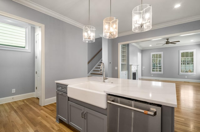 kitchen with open floor plan, light wood finished floors, stainless steel dishwasher, and a sink