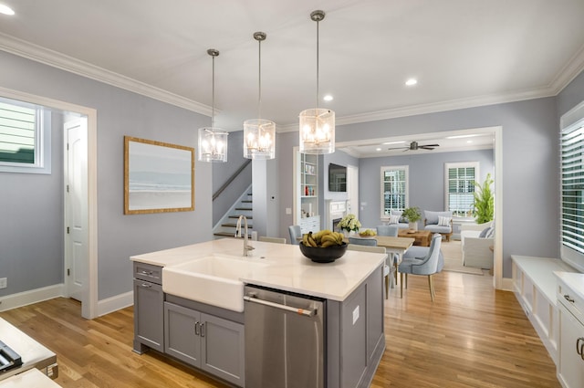 kitchen with stainless steel dishwasher, a sink, ceiling fan with notable chandelier, light wood-type flooring, and gray cabinetry