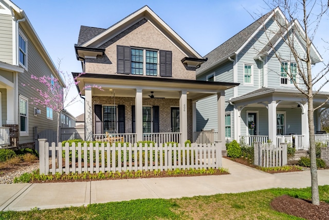 view of front facade with a porch, brick siding, and a fenced front yard