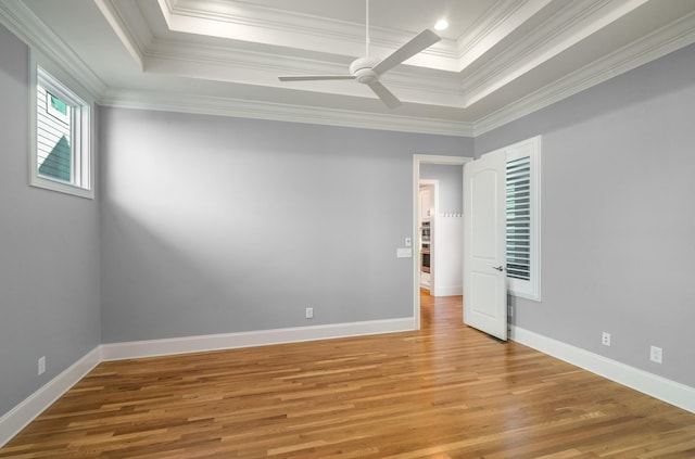 unfurnished room with a tray ceiling, crown molding, light wood finished floors, and a ceiling fan
