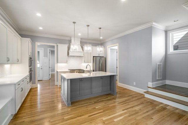 kitchen with a sink, stainless steel appliances, light countertops, custom range hood, and visible vents
