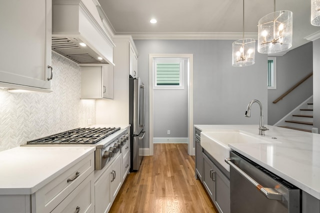 kitchen with stainless steel appliances, backsplash, a sink, hanging light fixtures, and custom exhaust hood