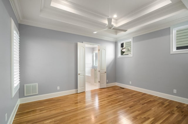 unfurnished bedroom with a raised ceiling, light wood-type flooring, visible vents, and crown molding