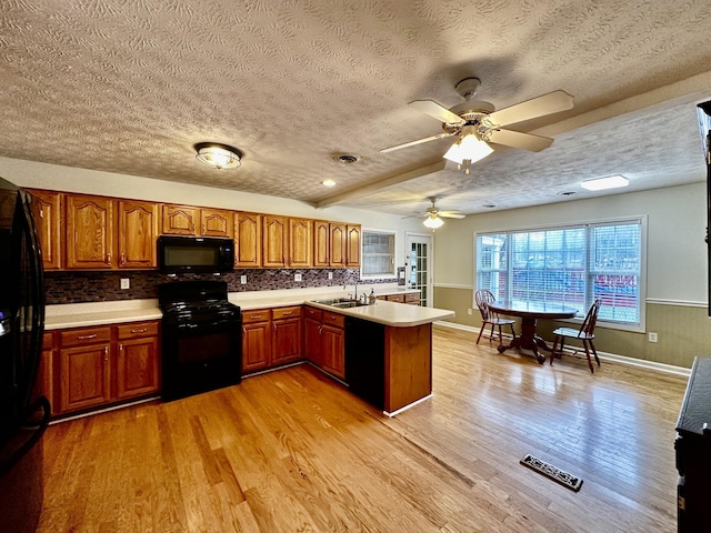 273 Chapel Rd, New Johnsonville, TN 37134 - kitchen featuring light countertops, light wood-style floors, a peninsula, black appliances, and brown cabinets