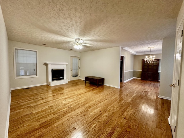 273 Chapel Rd, New Johnsonville, TN 37134 - unfurnished living room featuring a fireplace with raised hearth, baseboards, ceiling fan with notable chandelier, visible vents, and hardwood / wood-style floors