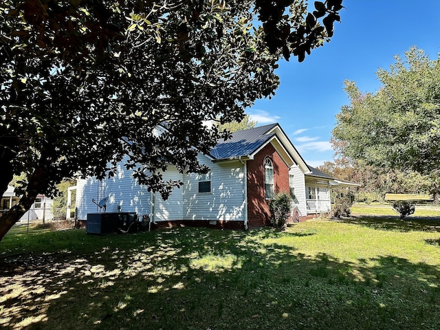 273 Chapel Rd, New Johnsonville, TN 37134 - view of property exterior featuring a lawn, metal roof, and central AC unit