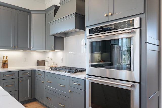 1428 Boardwalk Pl, Gallatin, TN 37066 - kitchen featuring tasteful backsplash, premium range hood, gray cabinetry, light stone countertops, and appliances with stainless steel finishes