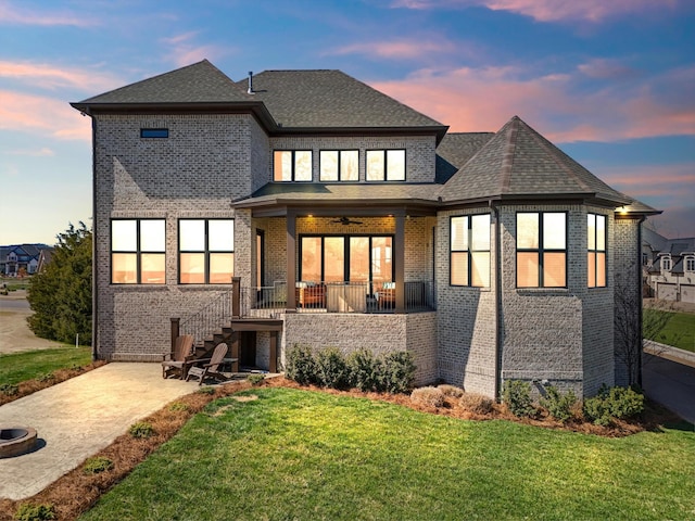 1428 Boardwalk Pl, Gallatin, TN 37066 - back of house at dusk featuring a patio, brick siding, a porch, a shingled roof, and a yard