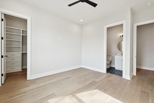 unfurnished bedroom with light wood-type flooring, ensuite bathroom, baseboards, a spacious closet, and a closet