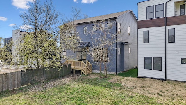 rear view of property featuring a lawn and fence
