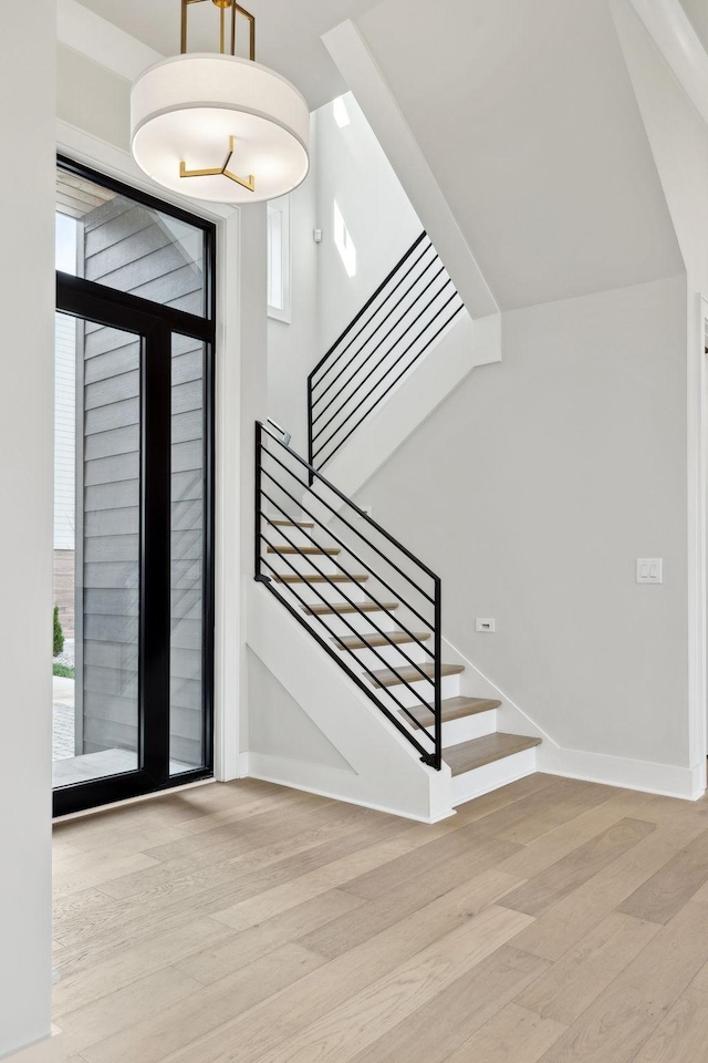 foyer entrance featuring baseboards, wood finished floors, and stairway
