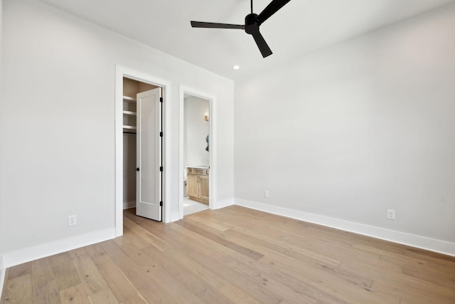 unfurnished bedroom with light wood-type flooring, baseboards, a spacious closet, recessed lighting, and ensuite bath