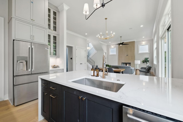 kitchen with ceiling fan with notable chandelier, a sink, appliances with stainless steel finishes, and crown molding