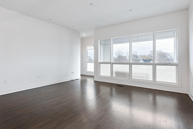 unfurnished room with dark wood-type flooring, baseboards, and visible vents