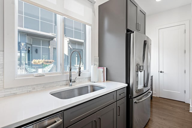 kitchen with light countertops, dark wood-style flooring, stainless steel appliances, gray cabinetry, and a sink