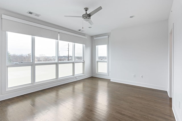 empty room with a ceiling fan, dark wood-style flooring, baseboards, and visible vents