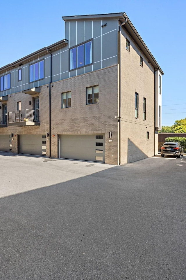 rear view of property featuring brick siding and a garage